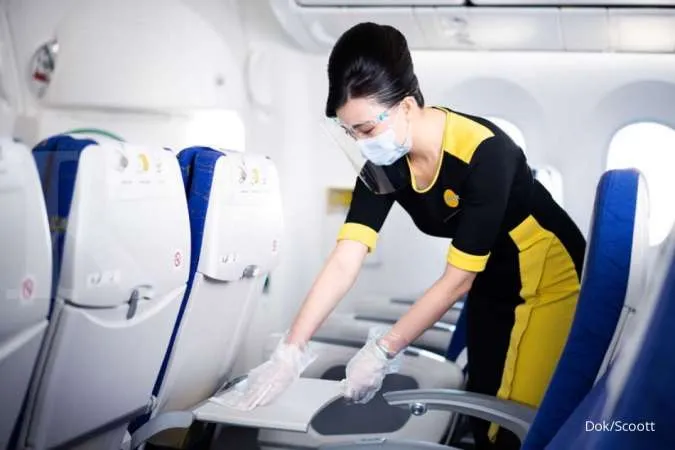Pramugari Scoot membersihkan kursi penumpang pesawat