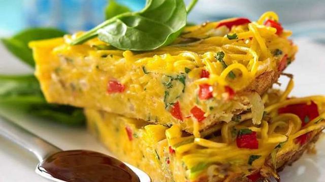 Sepotong omelet sosis lembut yang dipadukan dengan keju meleleh dan irisan sayuran segar, disajikan hangat untuk sarapan spesial