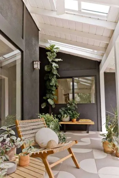 teras rumah dengan unsur kayu dan tanaman serta lantai warna krem
